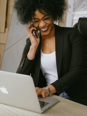 pexels photo 3727464 3727464 Smiling woman on phone call while working on a laptop in a stylish office.